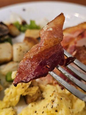 A fork holding a piece of nice size bacon.