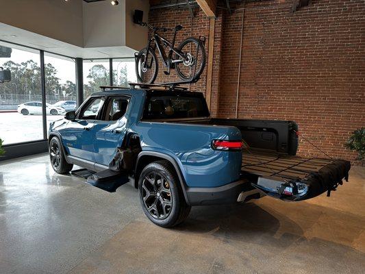 Rivian R1T equipped with on-road tires and loaded up with a bike and gear in the gear tunnel!