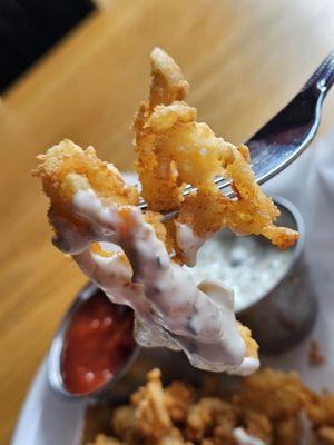 Clam Strips with the Tartar sauce on a fork getting ready to be tasted and savored.