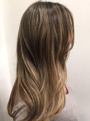 Balayage her hair using two tones of blondes to soften her dark natural hair