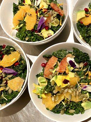 Kale, citrus, avocado salad with pepitas, pomegranate, flowers, and citrus-maple vinaigrette.