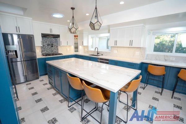 Blue kitchen cabinets with white mosaic glass designs and white counter tops