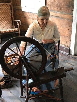 Spinning wool with a hand cranked wheel.