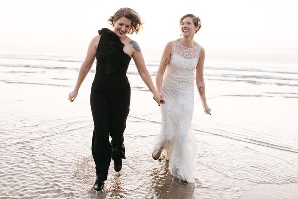 wedding couples runs through the surf at the Oregon coast