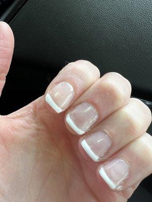 Scratched up nails, uneven french manicure, sides of nail aren't done, messy and rushed overall.