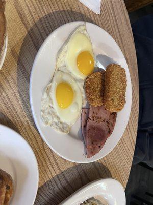 Sunny side up eggs and hash brown patties with ham