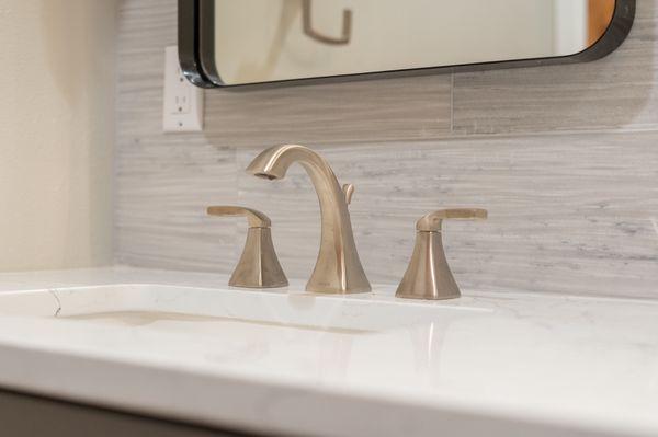 Up close photo of the modern sink fixtures and the backsplash of the vanity.