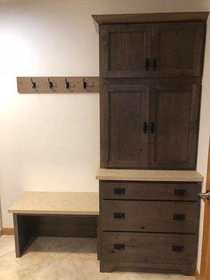 Mud room area cabinetry with bench and coat hooks.