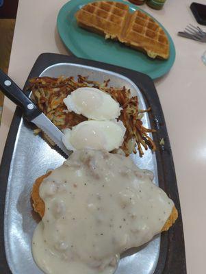 Chicken fried chicken with hashbrowns, poached eggs, and waffle.