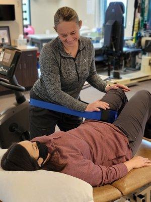 Using a mobilization belt to assist in stretching the hip joint.