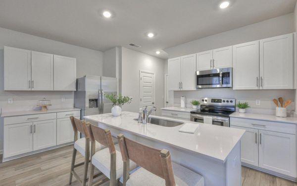 Spacious kitchen with quartz countertops including kitchen island and stainless steel appliances.