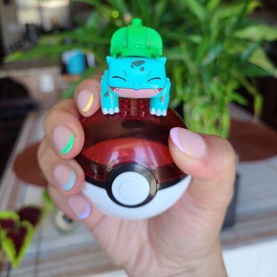 French manicured nails with rainbow tips (dip and gel) holding a PokeBall with Bulbasaur