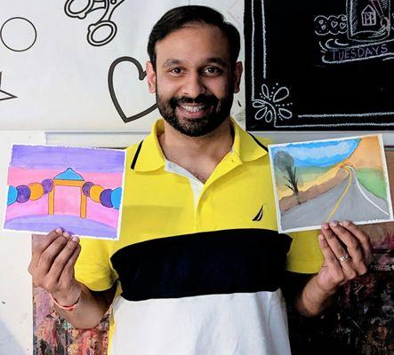 An adult student posing with his finished watercolor paintings.