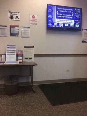 Information pamphlets on the table and electronic display announcing numbers called.