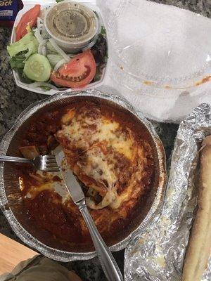 Lasagna dinner with two giant breadsticks and a side salad