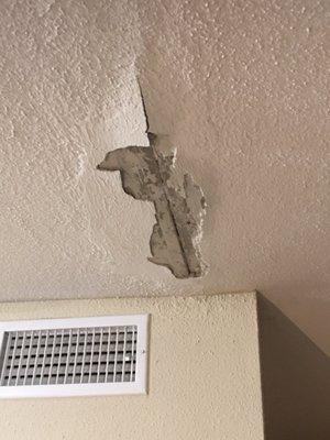 Hole in ceiling with peeling plaster