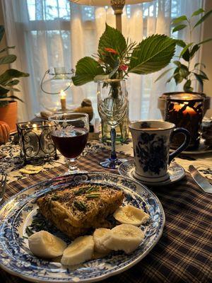 Romantic Breakfast Table, sausage egg casserole with sliced banana, a cup of coffee, and juice.