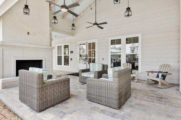 Outdoor lounge area with padded seats by the fireplace, complemented with ceiling fans at Lantower Edgewater