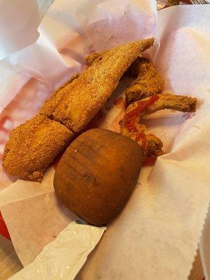 Two jumbo shrimp, one fried fish, and a roll as part of gumbo meal