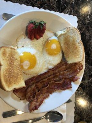 Sunny side up eggs and bacon with buttered toast