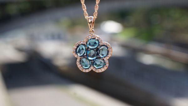 Rose cut London Blue Topaz framed in 14k rose gold and brilliant white diamonds in a floral style.