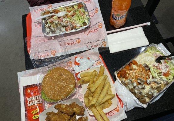 Chicken burger, chicken wings, French fries, chicken and lamb over rice, white sauce, and Fanta