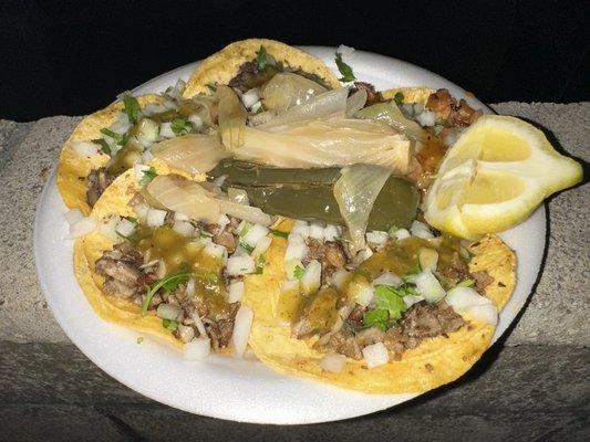 Tacos de tripa, cabeza and al pastor with grilled onions and chile in the center.