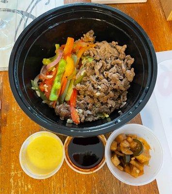 Beef fried rice bowl with two sauces and a delicious Korean side dish of pickled vegetables.