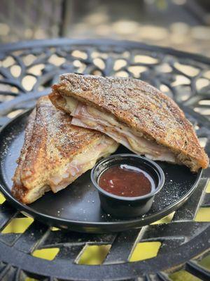 grilled cinnamon french toast pan bread, with smoked ham, turkey, and melted swiss cheese, all sprinkled with powdered sugar and served with