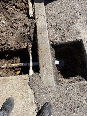 Repaired section of 2" pipe between asphalt and planter.