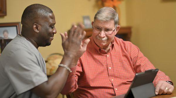 Our compassionate caregiver and client celebrate a tech milestone on the iPad with a high five, supporting learning and engagement at home.