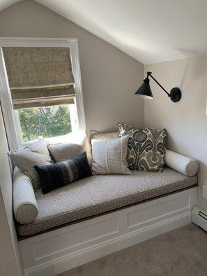 reading nook in primary bedroom with roman shades, upholstered bench cushion, and custom bolsters