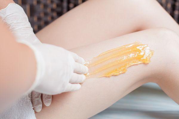 A trained technician applies warm sugar paste to remove hairs.