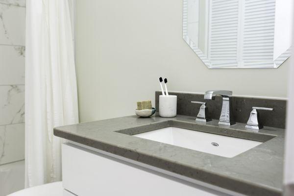 Undermounted sinks, grey quartz counter tops, marble-look tile showers.