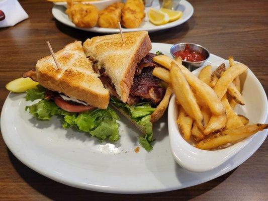 BLT sandwich with fries, Fish & Chips in the background