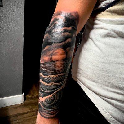 Ocean and sunset tattoo on arm