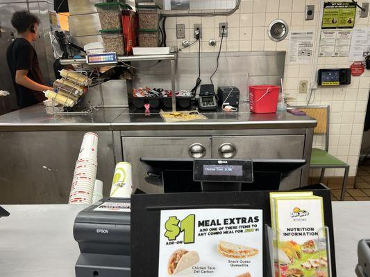 Partially eaten food and devices charging next to food prep area and sanitize bucket at the front counter.