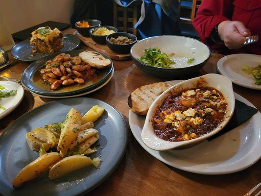 From top left: pastitsio, trio of dips, marouli, garithes saganaki, lemon potatoes, and giant beans.