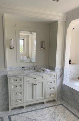 Luxurious vanity, backsplash and tub crafted from marble. The floor features tiles in neutral tones giving a classic touch.