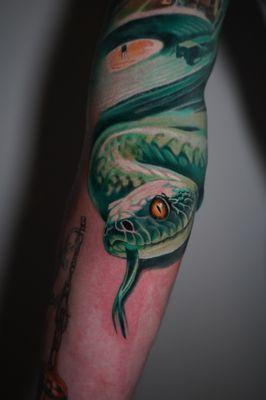 This vibrant snake tattoo coils with lifelike detail, its piercing eyes and scales capturing the essence of stealth and power.