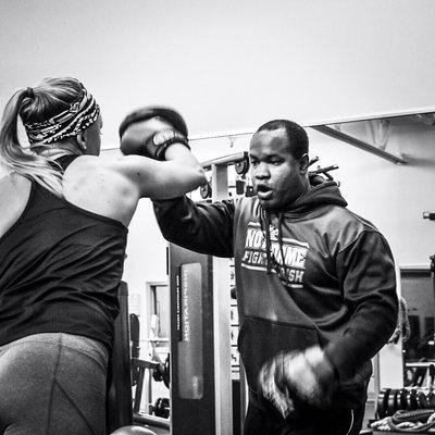 Trainer Rich Ford working with a client on her boxing skills