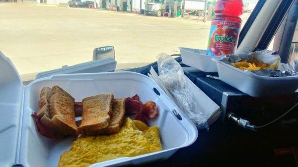 scrambled eggs bacon toast and hash browns and a bottle of cranberry juice dashboard dining