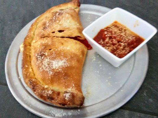 Perfectly baked calzone with extra sauce on the side if you ask