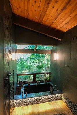 Spa like sunken tub with earth like rocks and lighting.