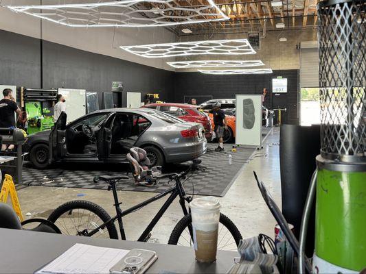 The shop space as seen from the customer lounge. Several cars are being worked on.