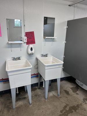 Clean bathrooms with sinks, shelves, mirrors, soap and hand dryers provided