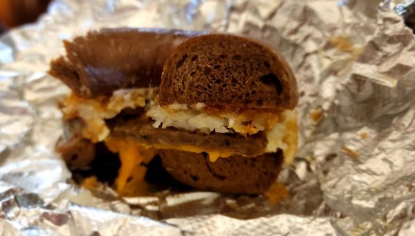 Sausage, egg & cheddar on a pumpernickel bagel with a hashbown topper