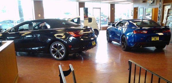 Part of the showroom, featuring (from L to R), a Buick Cascada convertible, a Chevrolet (sub)compact, and a Chevrolet Camaro.