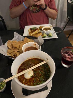 Birria ramen, chips and salsa, hibiscus margarita, birria grilled cheese, tacos.