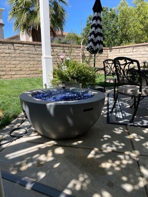 Propane fire pit (refinished), fire glass (3 bags), glass wind screen, umbrella, rolling umbrella base, poolside umbrella table.